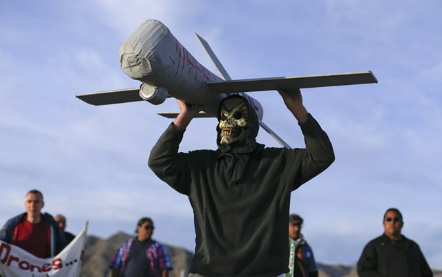 Manifestante mascarado carrega um modelo de drone usado pela Força Aérea nos EUA (Foto: Julie Jacobson/AP).