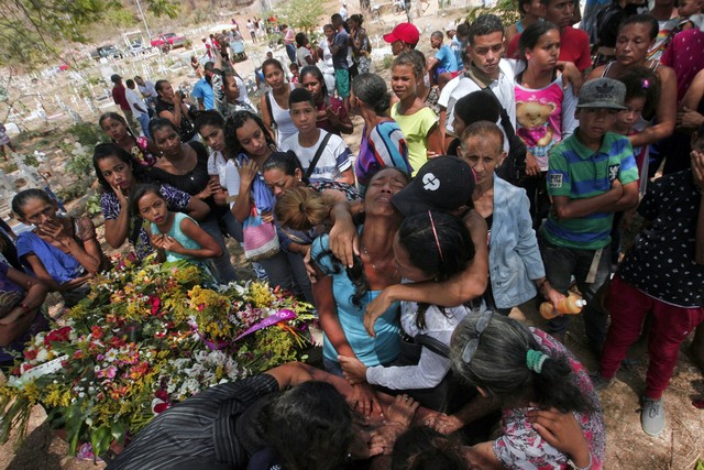 Parentes se emocionam durante enterro de detento morto em incêndio em prisão na cidade de Valência, na Venezuela (Foto: Juan Carlos Hernandez/AFP).