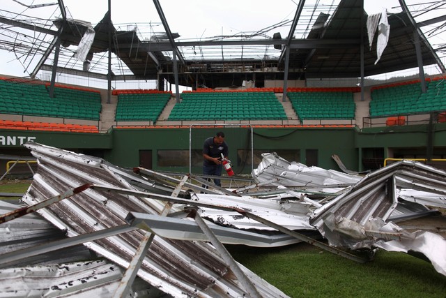 Um homem encontra um extintor de incêndio entre os escombros do estádio de beisebol Felix 'Nacho' Millan em Yabucoa, Porto Rico, depois que o furacão Maria atingiu a ilha em setembro de 2017 (Foto: Alvin Baez/Reuters).