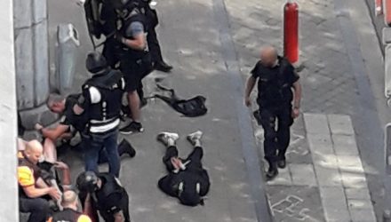 Forças especiais da polícia são vistas em Liège, na Bélgica, próximas de um homem no chão, supostamente o atirador (Foto: Isabelle Freres/RTL Belgium/Reuters).