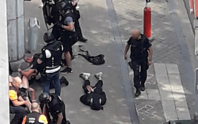 Forças especiais da polícia são vistas em Liège, na Bélgica, próximas de um homem no chão, supostamente o atirador (Foto: Isabelle Freres/RTL Belgium/Reuters).
