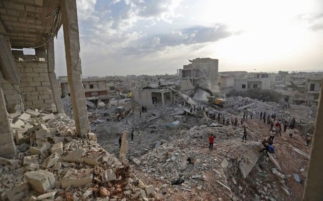 Sírios caminham sobre destroços em Zardana, em Idlib, nesta sexta-feira (8) (Foto: Omar Haj Kadour / AFP).