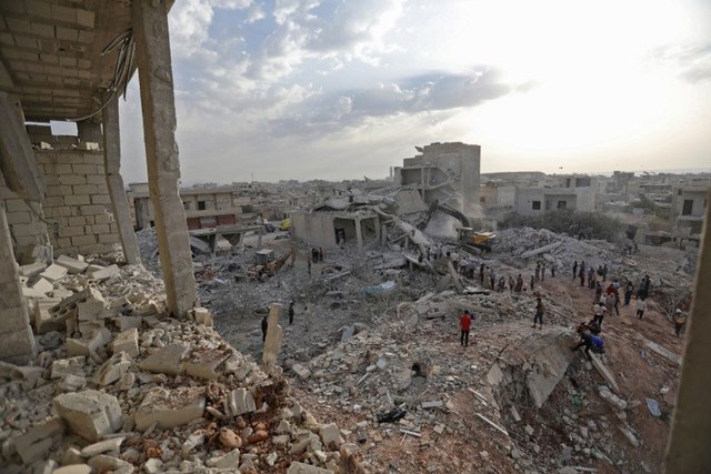 Sírios caminham sobre destroços em Zardana, em Idlib, nesta sexta-feira (8) (Foto: Omar Haj Kadour / AFP).
