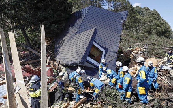 Equipes de resgate procuram sobreviventes de uma casa danificada cidade de Atsuma (Foto: Kyodo / via Reuters).