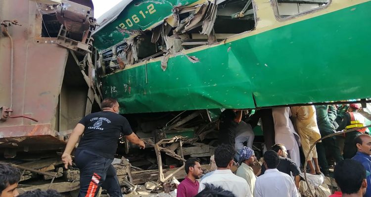 Socorristas paquistaneses e moradores se reúnem em volta dos destroços de trens que se chocaram no Paquistão na quinta-feira (11) — Foto: STR / AFP Photo.