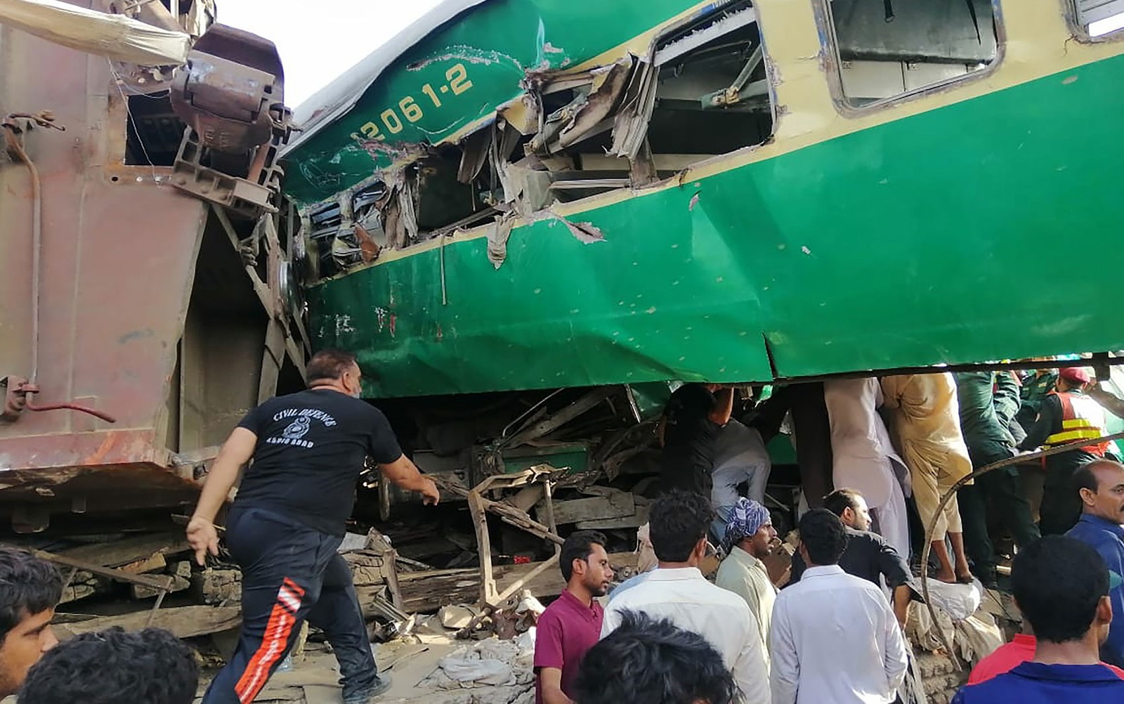 Socorristas paquistaneses e moradores se reúnem em volta dos destroços de trens que se chocaram no Paquistão na quinta-feira (11) — Foto: STR / AFP Photo.