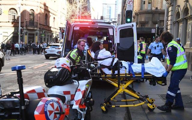 Mulher é levada para um hospital em Sydney, na Austrália, depois de ser esfaqueada nesta terça-feira (13) por um homem que tentou atingir várias pessoas no centro da cidade. — Foto: Dean Lewins/AAP Image via AP.