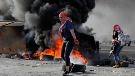 Manifestante palestina é vista na frente de pneus queimados durante protesto anti-Israel perto do assentamento de Beit El na Cisjordânia ocupada por Israel neste sábado (16) — Foto: Mohamad Torokman/Reuters.