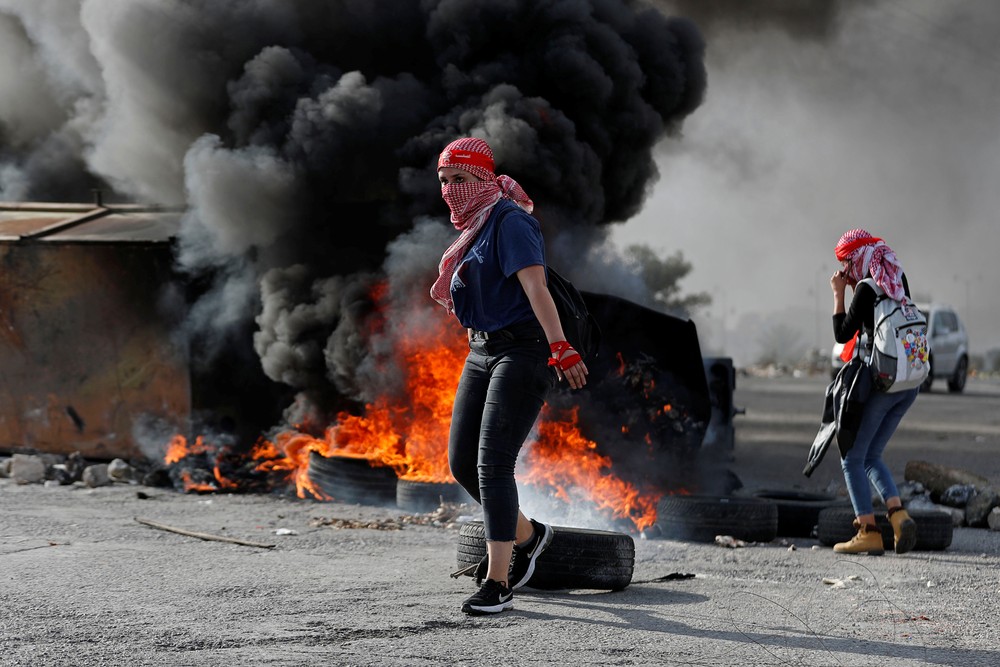 Manifestante palestina é vista na frente de pneus queimados durante protesto anti-Israel perto do assentamento de Beit El na Cisjordânia ocupada por Israel neste sábado (16) — Foto: Mohamad Torokman/Reuters.