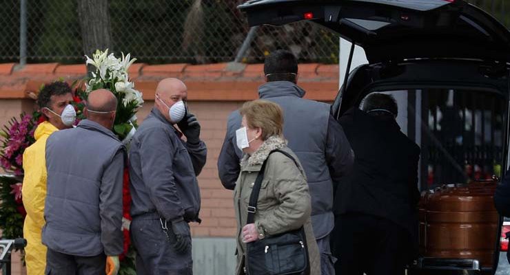 Agentes funerários carregam o caixão com vítima de Covid-19, no cemitério em Leganes, na Espanha, na terça-feira (24) — Foto: Manu Fernandez / AP.