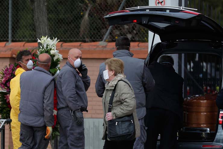 Agentes funerários carregam o caixão com vítima de Covid-19, no cemitério em Leganes, na Espanha, na terça-feira (24) — Foto: Manu Fernandez / AP.