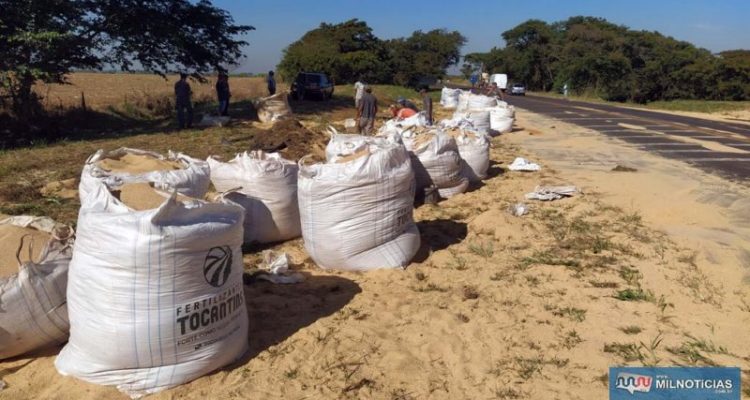 Trabalhadores contratados pela empresa dona da carga e do caminhão recolhem o material esparramado pela pista. Foto: MANOEL MESSIAS/Agência