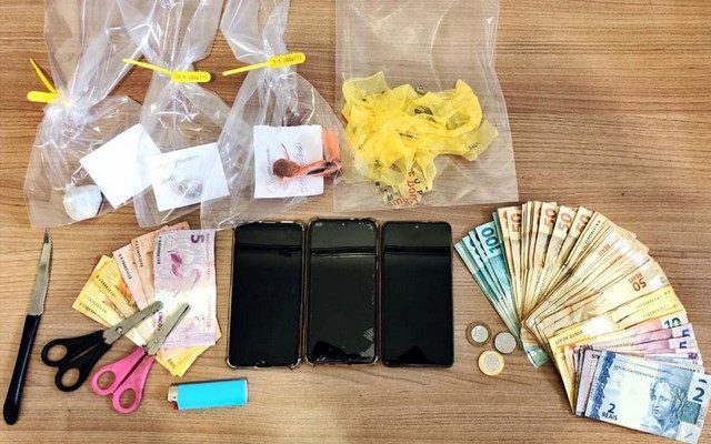 Foram apreendidos 17g Maconha, 3 telefones celulares, 2 Tesouras, 1 Faca, 1 Isqueiro, 1 Sacola Plástica, além de um total de R$ 3.611,50. Foto: DIVULGAÇÃO/PM