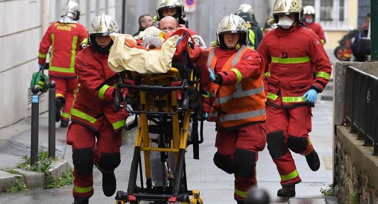 Bombeiros franceses socorrem ferido perto das antigas instalações do jornal 'Charlie Hebdo', em Paris, em 25 de setembro — Foto: Alain Jocard / AFP.