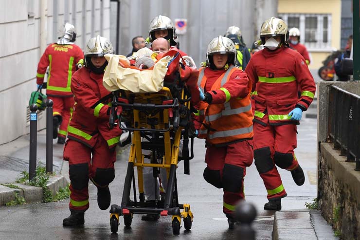 Bombeiros franceses socorrem ferido perto das antigas instalações do jornal 'Charlie Hebdo', em Paris, em 25 de setembro — Foto: Alain Jocard / AFP.